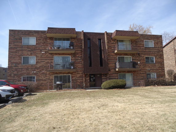 Front view of a multi-story apartment building with balconies.