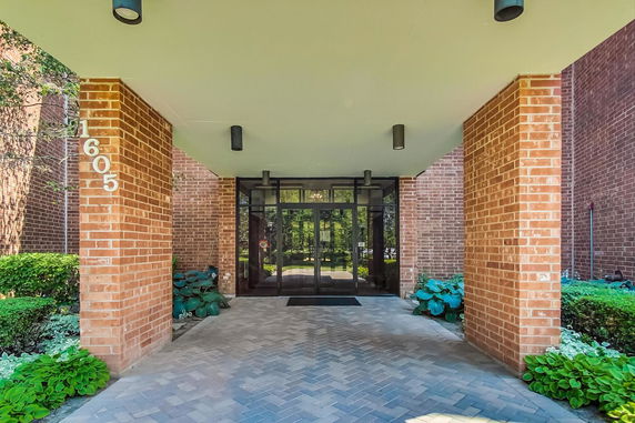 Front view of a brick building entrance with glass doors and columns.