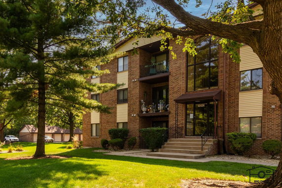 Front view of a multi-story brick apartment building with balconies.