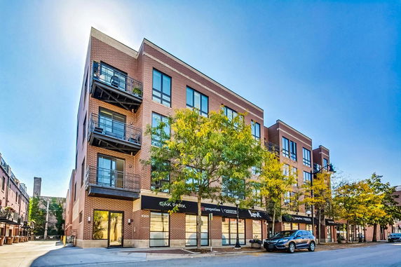 Front view of a multi-story brick building with balconies and commercial space on the ground floor.