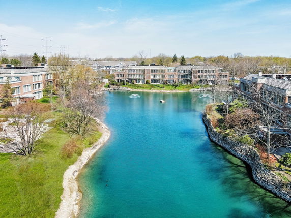 Panoramic view of residential buildings around a lake with clear blue water.
