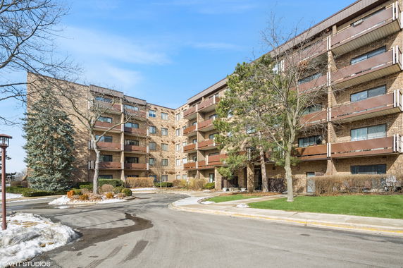 Front view of a multi-story brick apartment building with balconies.