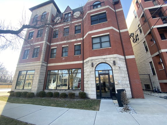 Front view of a multi-story brick building with large windows.