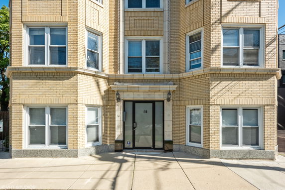 Front view of a multi-story brick building with multiple windows and a central entrance.
