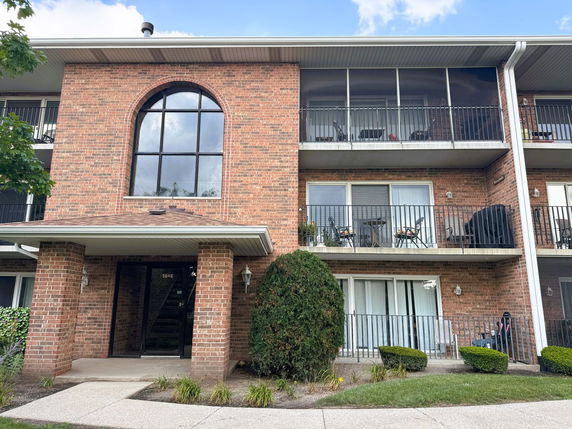 Front view of a multi-story brick apartment building with balconies.