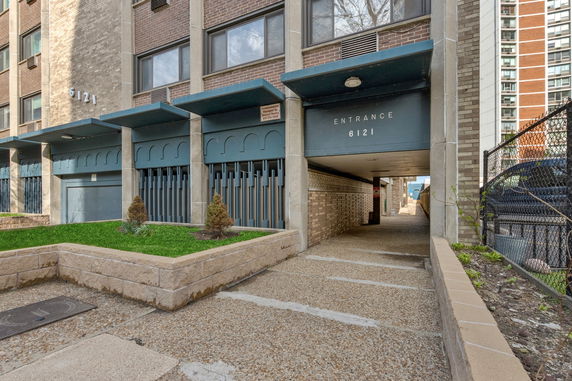 Front view of a multi-story building entrance with brick facade and decorative elements.