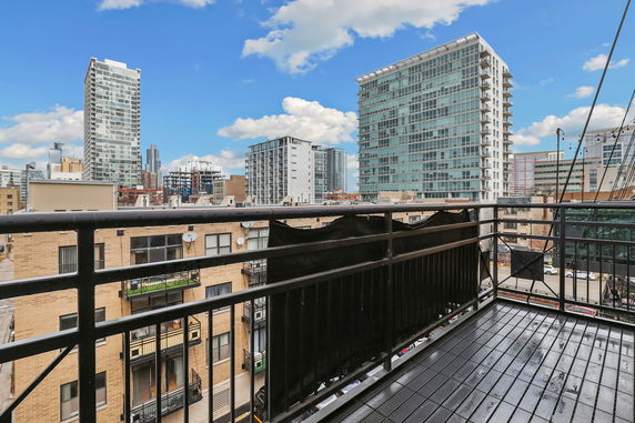 View of urban buildings from a balcony in a high-rise setting.