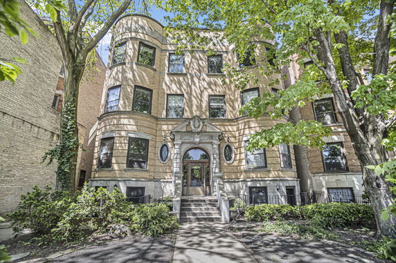 Front view of a multi-story residential building with numerous windows and decorative entrance.