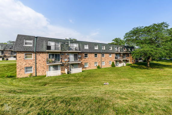 Front view of a three-story brick apartment building with multiple balconies.