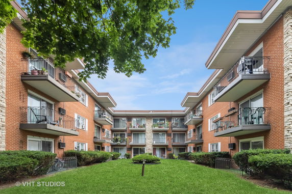 Front view of a multi-story brick apartment complex with balconies.