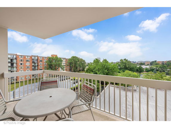 View from a balcony showing surrounding buildings and greenery.