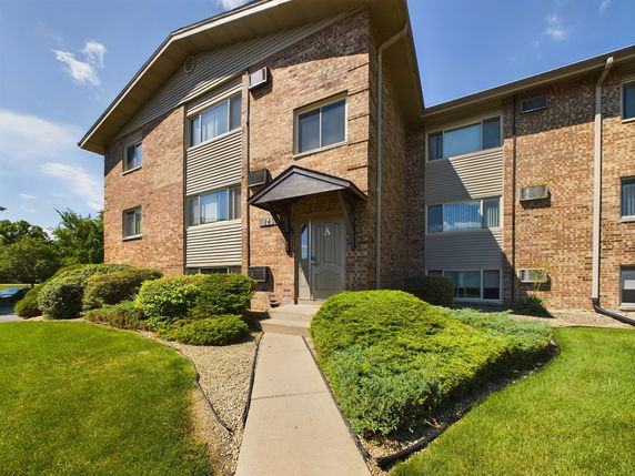 Front view of a multi-story brick building with multiple windows and a small entrance porch.