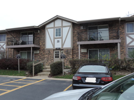 Front view of a two-story brick apartment building with balconies and a central entrance.