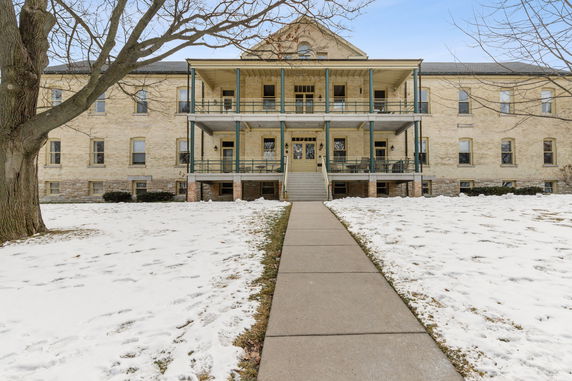 Front view of a large building with a double porch and multiple windows.
