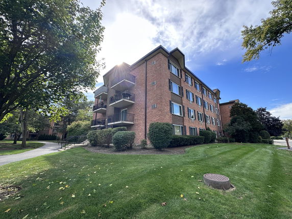 Front view of a four-story brick apartment building with balconies.