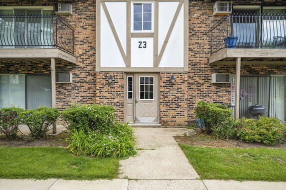 Front view of a brick apartment building with balconies and a central entrance door.