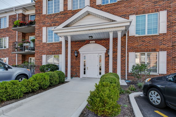 Front view of a multi-story brick building with white trim and balconies.