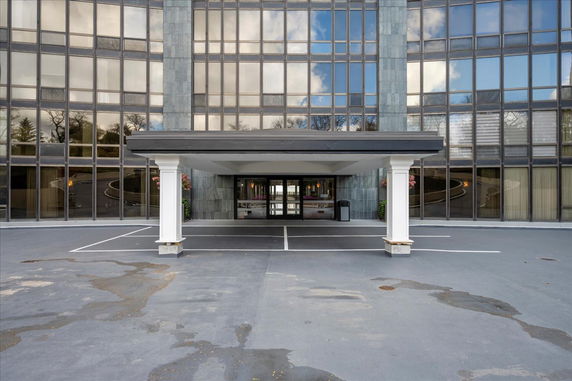 Front view of a modern glass-fronted building entrance with covered drive-through area.