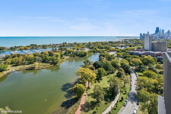 Panoramic view of a cityscape with a park, river, and distant skyline.