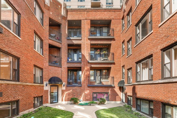 Front view of a brick apartment building with balconies.