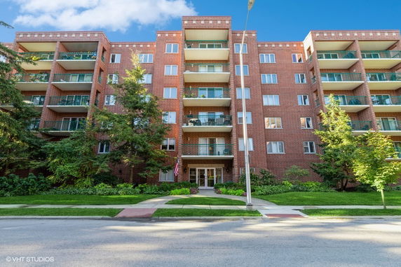 Front view of a multi-story brick apartment building with balconies.