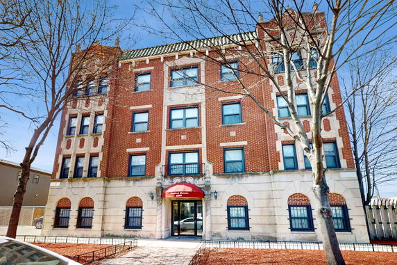Front view of a multi-story brick building with decorative arched windows and a central entrance.