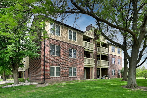 Front view of a multi-story apartment building with brick facade and balconies.