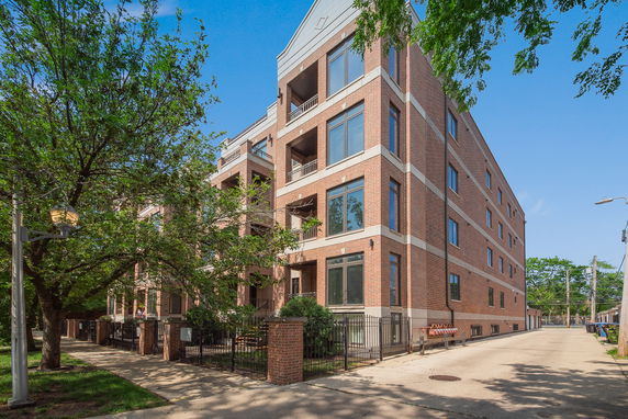 Front view of a multi-story brick building with large windows and balconies.