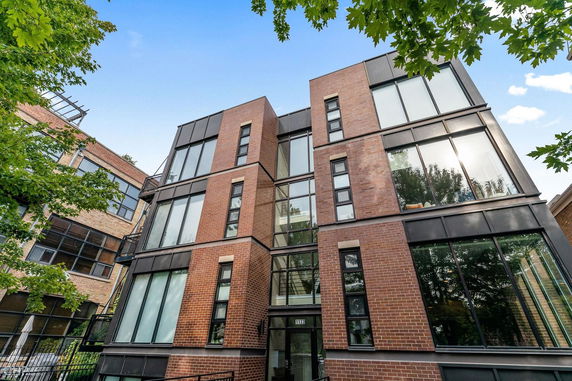 Front view of a modern multi-story brick building with large windows.