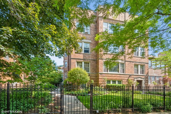 Front view of a multi-story brick building with a fenced yard.