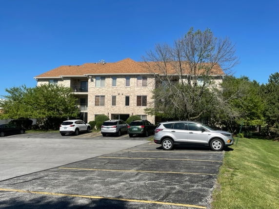 Front view of a multi-story residential building with a parking area in front.