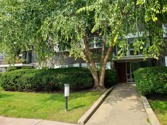 Front view of a multi-story apartment building with a walkway and entrance.