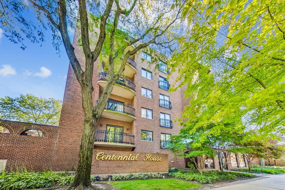 Front view of a multi-story brick building named Centennial House with balconies.