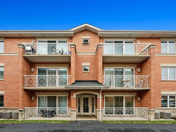 Front view of a three-story brick apartment building with balconies.
