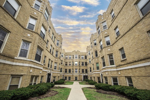 Front view of a multi-story brick apartment building with multiple windows.