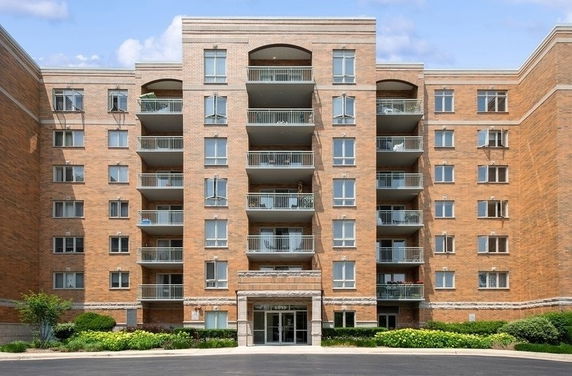 Front view of a multi-story brick apartment building with balconies.
