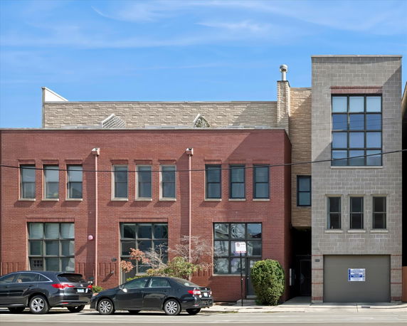 Front view of a mixed brick and stone building with multiple windows and a garage.