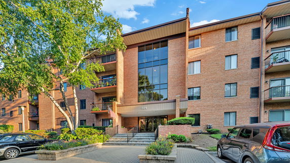 Front view of a multi-story brick apartment building with balconies.
