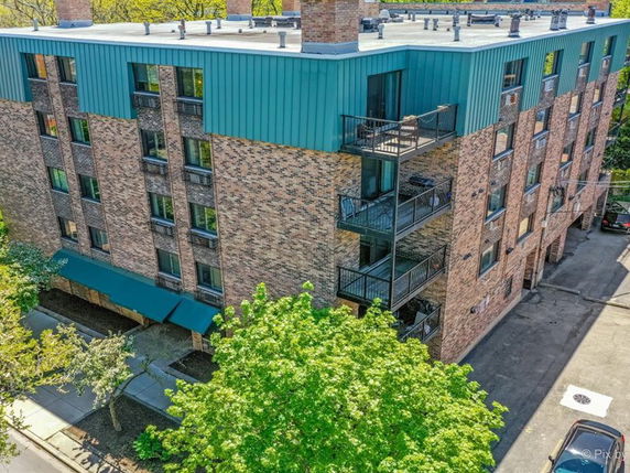 Aerial view of a multi-story brick building with balconies and a green roof.