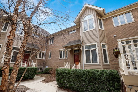Front view of a two-story townhouse with brown brick and siding.