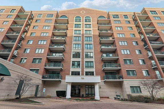 Front view of a multi-story brick apartment building with balconies.