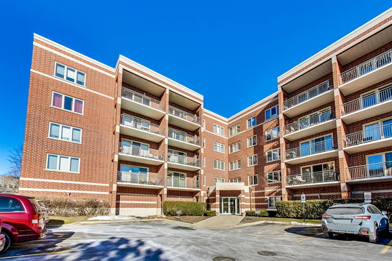 Front view of a multi-story brick apartment building with balconies.