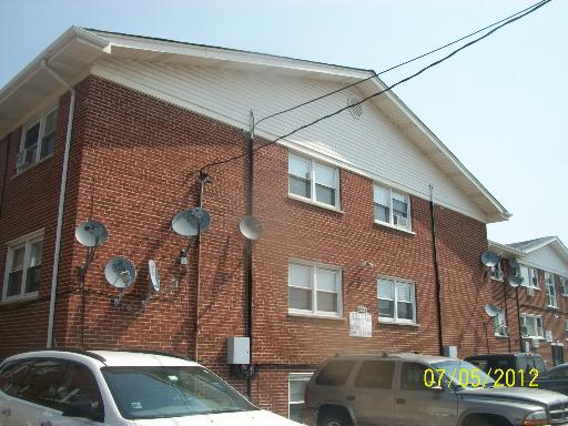 Front view of a multi-story brick building with multiple satellite dishes attached.