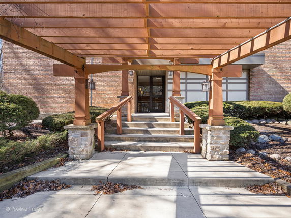 Front view of a building with a wooden pergola and steps leading to the entrance.