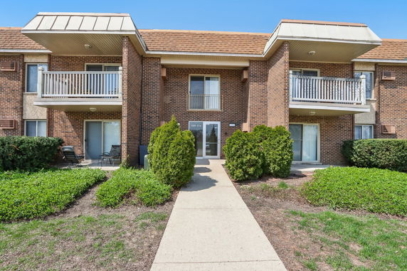 Front view of a brick apartment building with balconies.
