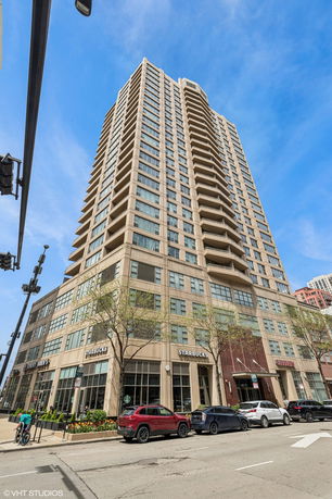 Front view of a tall multi-story building with commercial shops on the ground floor.