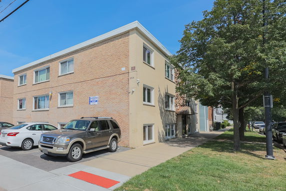 Front view of a two-story brick apartment building with parking space in front.