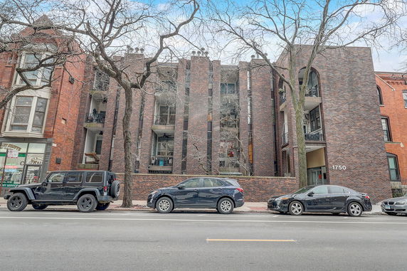 Front view of a brick multi-story apartment building with balconies.