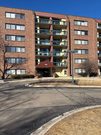 Front view of a multi-story brick apartment building with balconies.
