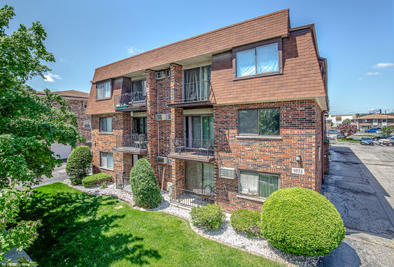 Front view of a multi-story brick building with small balconies.